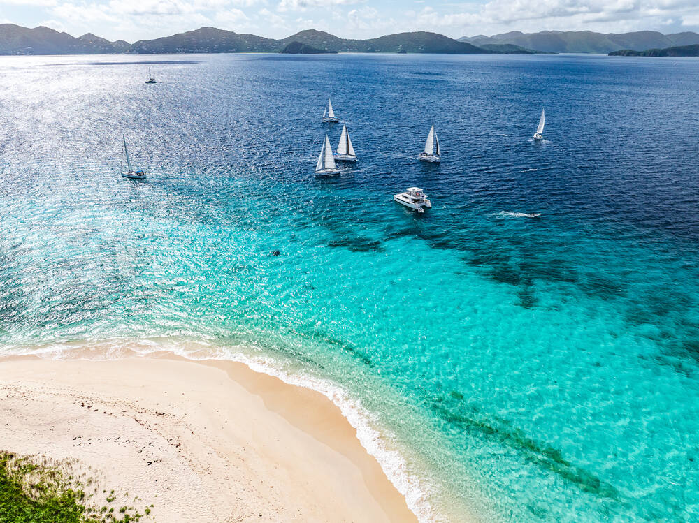Aerial view of the fleet anchored off a white sand beach